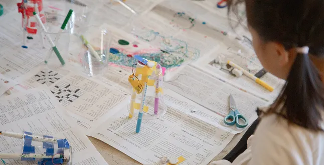 Child with newspapers, tools and a pen robot
