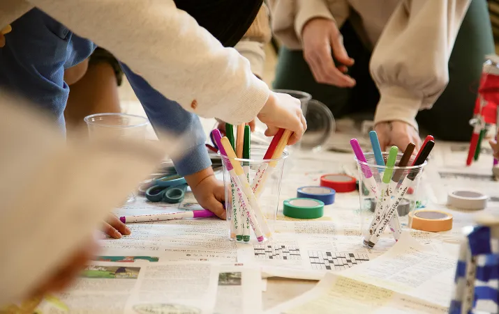 Kids working with markers, newpapers, trinkets